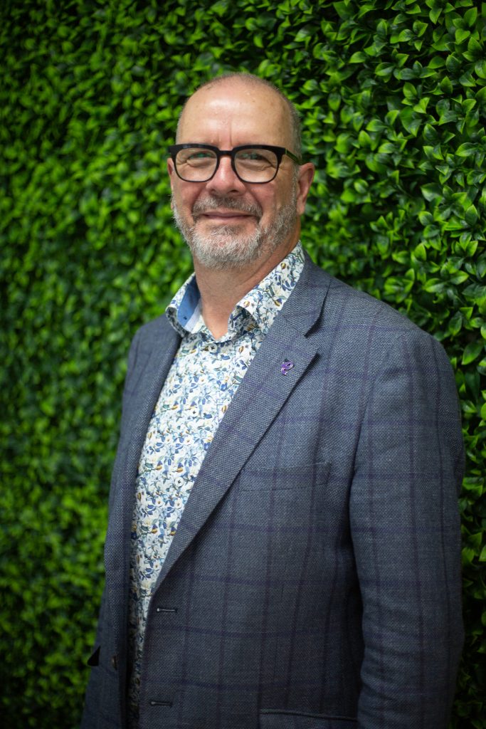 Graeme Shears in suit in front of greenery